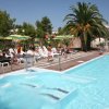 Piscina all'aperto con lettini e ombrelloni verdi e gialli.