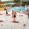 Donne partecipano a una lezione di fitness su pedane vicino alla piscina.