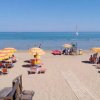 Spiaggia sabbiosa con ombrelloni gialli e arancioni, bagnanti in mare.