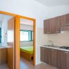 Un angolo cottura con mobili in legno e due porte aperte che conducono a una stanza con letto.