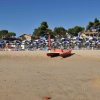 Spiaggia con pedalò e ombrelloni blu e bianchi.