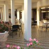 Terrazza coperta con colonne bianche, tavoli, sedie e vasi di fiori.