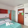 Letto matrimoniale con copriletto azzurro, armadio e porta d'ingresso con climatizzatore sopra.
