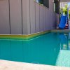 Piscina con scivolo blu accanto a un edificio moderno.