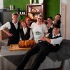 Gruppo di persone in divisa con dolce su tavolo.