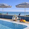 Piscina con ombrelloni blu e snack vista mare.
