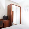 Camera d'albergo con armadio a specchio, scrivania, sedia e TV.