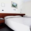 Letto matrimoniale e letto singolo sotto un quadro, telefono sul comodino.