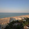 Vista aerea di una spiaggia affollata con ombrelloni e mare calmo.