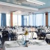 Una sala da pranzo con tavoli apparecchiati e sedie nere, tende blu alle finestre.