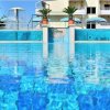 Piscina blu con cascate e ombrelloni, edificio bianco sullo sfondo.