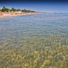 Spiaggia con mare limpido e cielo blu.