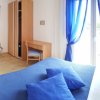 Camera con letto blu, scrivania e armadio, tenda blu e finestra aperta.
