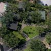 Vista aerea di una piscina e area verde con alberi e percorsi pedonali.