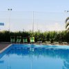 Piscina con palme e lettini verdi, cielo sereno.