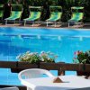 Piscina vuota con lettini verdi e fiori sul bordo.