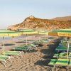 Spiaggia con lettini e ombrelloni verdi e gialli.