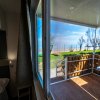 Vista dall'interno di una stanza su una terrazza con tavolo bianco e un giardino soleggiato oltre.