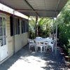 Veranda con tavolo e sedie di plastica accanto a una casa mobile con porta finestra.