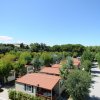 Vista aerea di un campeggio con casette tra alberi e viali alberati.
