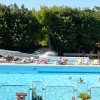 Grande piscina con scivoli d'acqua, persone che nuotano e si rilassano su lettini.