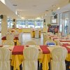 Sala da pranzo con tavoli apparecchiati, tovaglie rosse e gialle.
