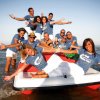 Gruppo di persone sorridenti su un pedalò al mare.
