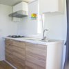Cucina moderna con piano cottura a gas e lavello, mobili in legno chiaro.