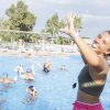 Persone sorridenti in piscina durante un'attività di gruppo all'aperto.
