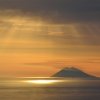 Tramonto sul mare con un'isola all'orizzonte.