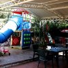 Area giochi coperta con scivolo blu e giochi per bambini su una terrazza.