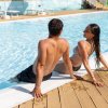 Due persone in costume da bagno sedute a bordo piscina.