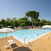 Piscina all'aperto con ombrelloni bianchi e lettini su una terrazza in legno.