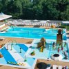 Una piscina con strutture per bambini e molte sdraio disposte intorno.
