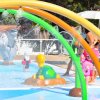 Bambini giocano in una piscina con scivoli e figure di animali colorati.