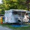 Camper bianco parcheggiato con sedie pieghevoli all'aperto.