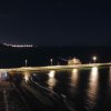 Molo illuminato di notte con riflessi sull'acqua, vista dall'alto.