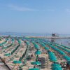 Spiaggia con file di ombrelloni verdi allineati, vista mare in lontananza.