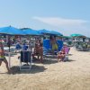 Persone sotto ombrelloni blu su una spiaggia affollata.