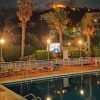 Piscina notturna illuminata con palme e luna sullo sfondo.