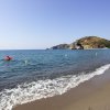 Spiaggia sabbiosa con onde che si infrangono e un kayak nel mare aperto.