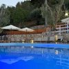 Piscina illuminata con ombrelloni e lettini.