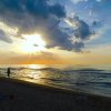 Tramonto su una spiaggia con persone che camminano.
