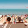 Due persone sedute osservano la spiaggia affollata.