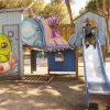 Un bambino scivola da uno scivolo vicino a una struttura di gioco.