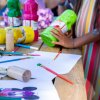 Materiali da disegno e colori su un tavolo con mani di bambini.