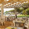 Ristorante all'aperto con tavoli apparecchiati, vista sulla piscina e giardino.