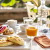 Colazione con succo, caffè, focaccine e ciambelle su un tavolo all'aperto.