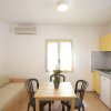 Cucina con tavolo e sedie, divano a destra, cucina gialla a sinistra.