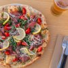 Pizza con fette di limone, pomodori e rucola.